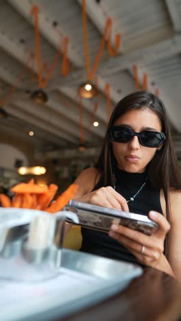 joven usando el teléfono en un café mientras come papas fritas