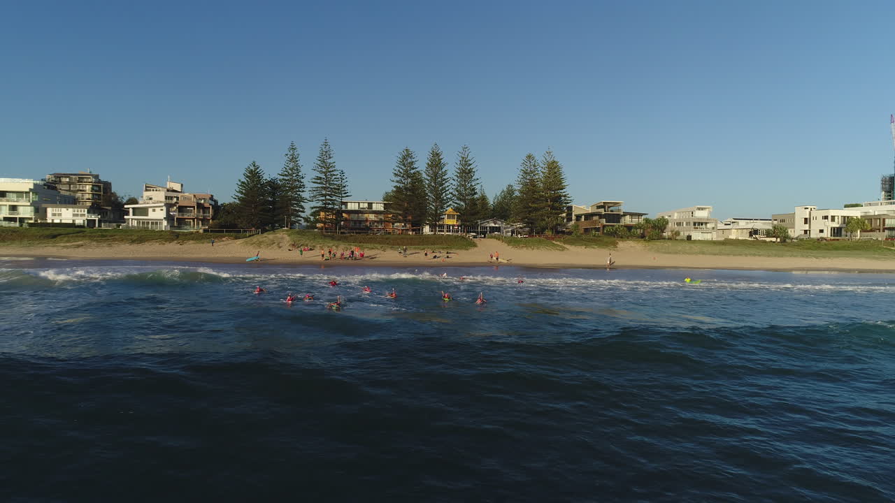 Aerial view of a group of Nippers paddling out into the ocean during a morning training session at Mermaid Beach Gold Coast Australia