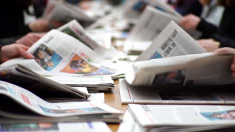 a group engaged in collaborative discussion over current events: an insightful look at people sharing perspectives amidst a sea of newspapers