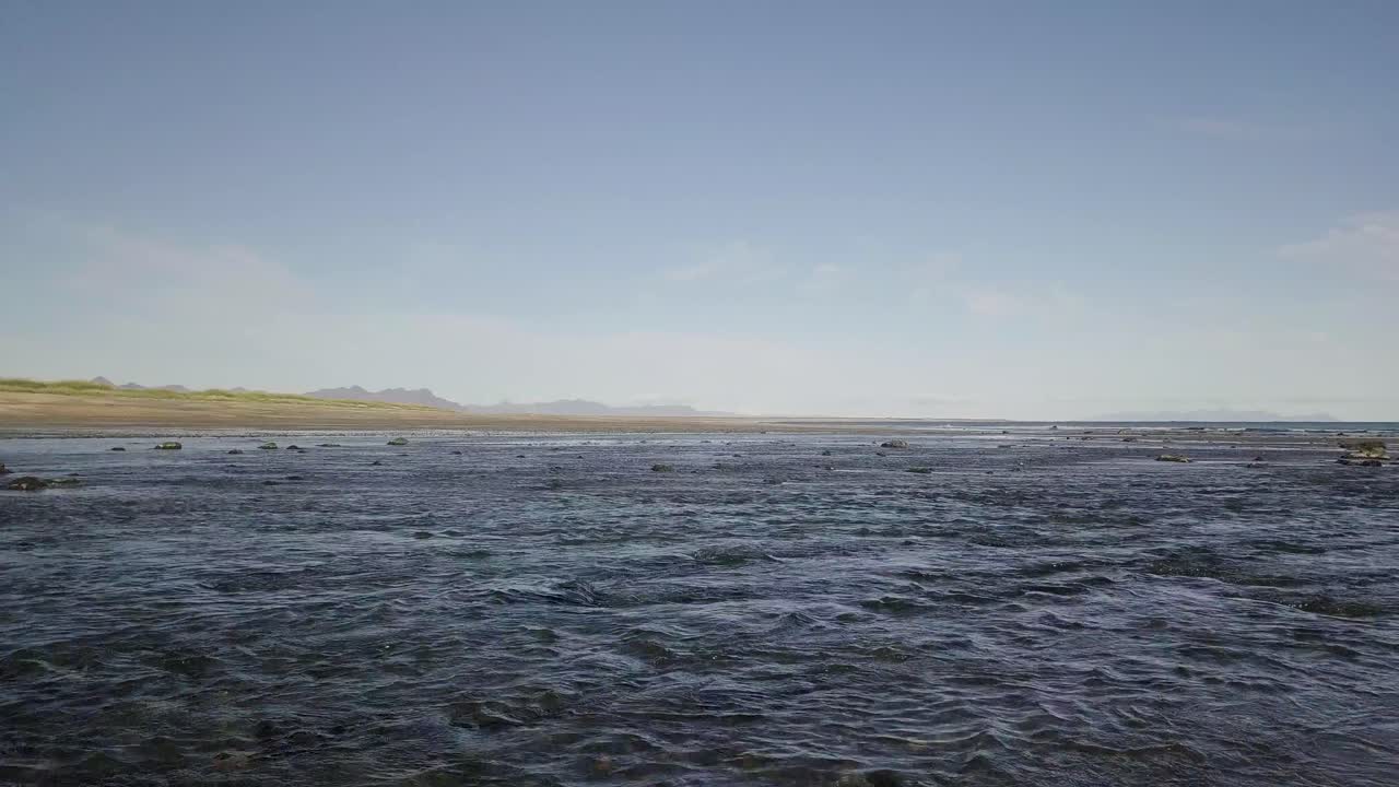 vuelo bajo sobre la playa y el océano bajo el sol durante el verano soleado en la península de snaefellsness, islandia
