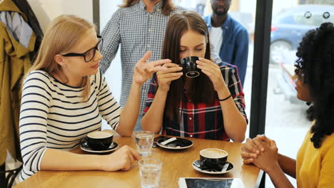 vista de cerca de amigas caucásicas y afroamericanas hablando y riéndose sentadas en una mesa en un café