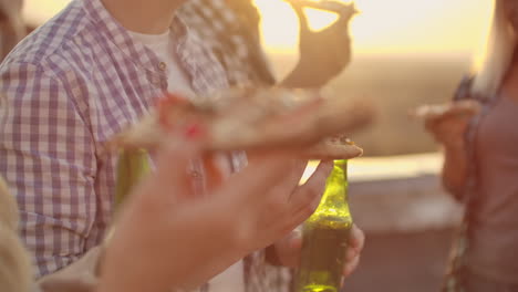 A-young-man-eat-piece-of-hot-pizza-and-drink-beer-on-the-party-with-his-friend.