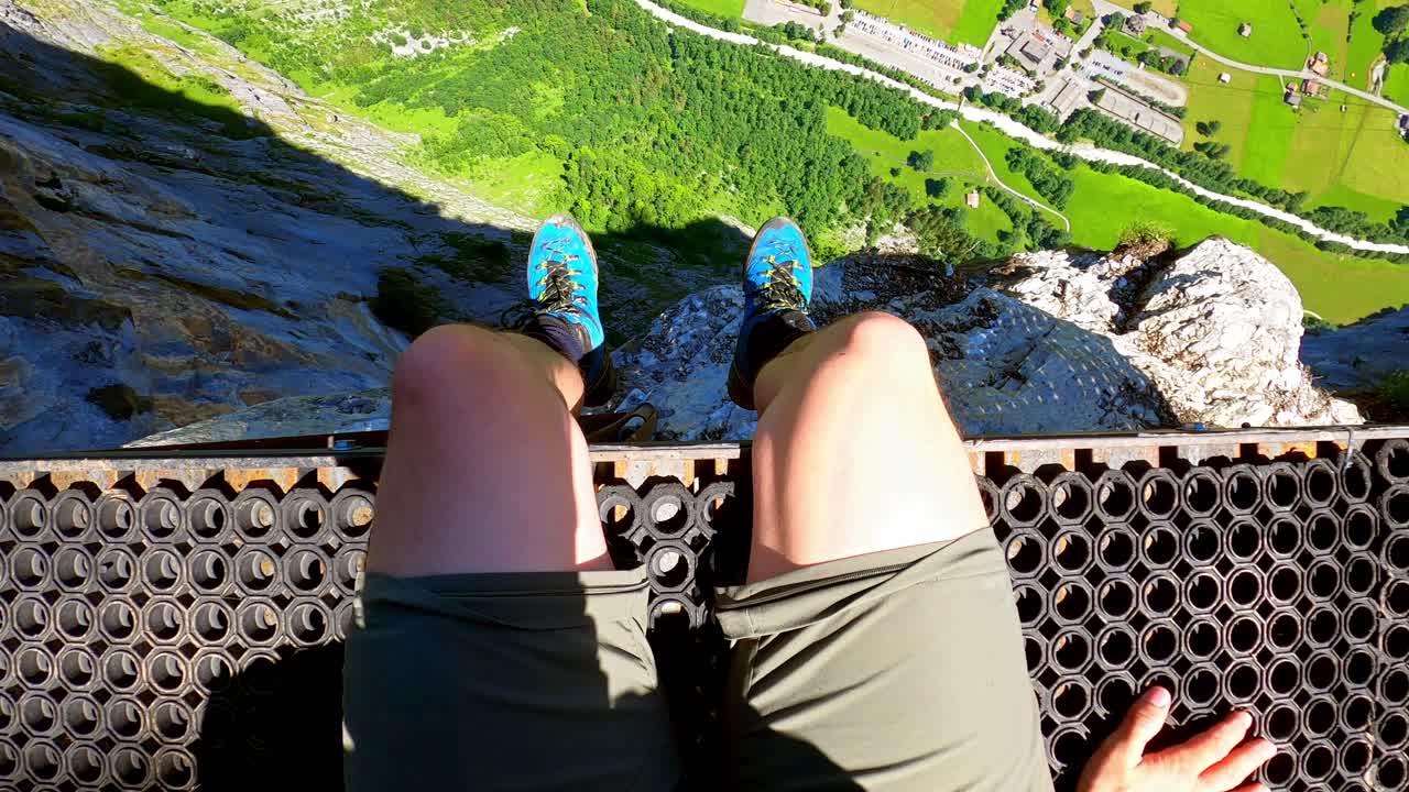 한 남자가 베이스 점퍼와 윙 수트를 입은 사람들을 위해 플랫폼에 앉아 있습니다.