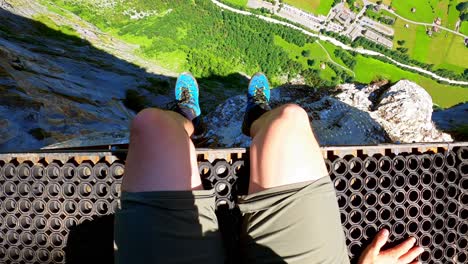 a man sits on a platform for base jumpers and people with wing suits