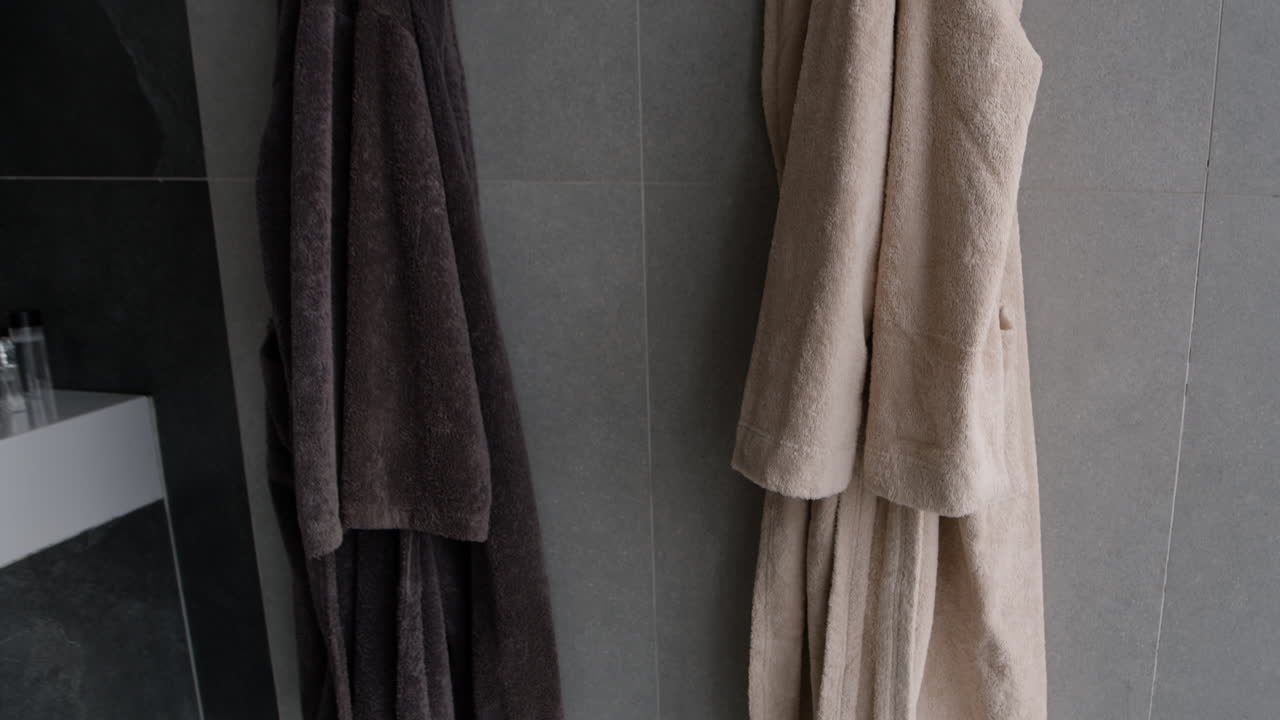 Two bathrobes hanging in a bathroom
