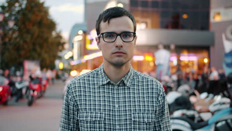 man in glasses on a city street at night