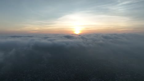 Toma-Aérea-De-Drones-De-Nubes-Oscuras-Sobre-La-Ciudad-Con-El-Sol-Poniéndose-Al-Fondo-En-Umerkot,-Tharparkar,-Pakistán-En-Una-Noche-Nublada