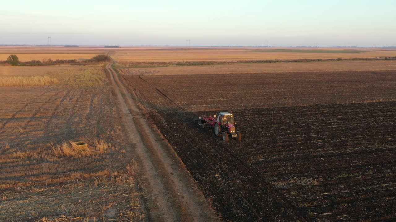 vista lateral aérea de un tractor que arrastra una harra de disco sobre un campo agrícola, tierras de cultivo