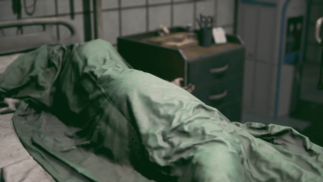Examination table covered with a green sheet in a dimly lit hospital room