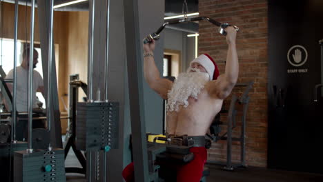 papá noel fuerte haciendo press de banca en el gimnasio. entrenamiento de deportista en club deportivo