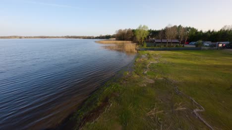 FPV-Drohne-Schoss-Tief-über-Strand-Und-Schilf-Am-Masurensee-Im-Sonnigen-Polen