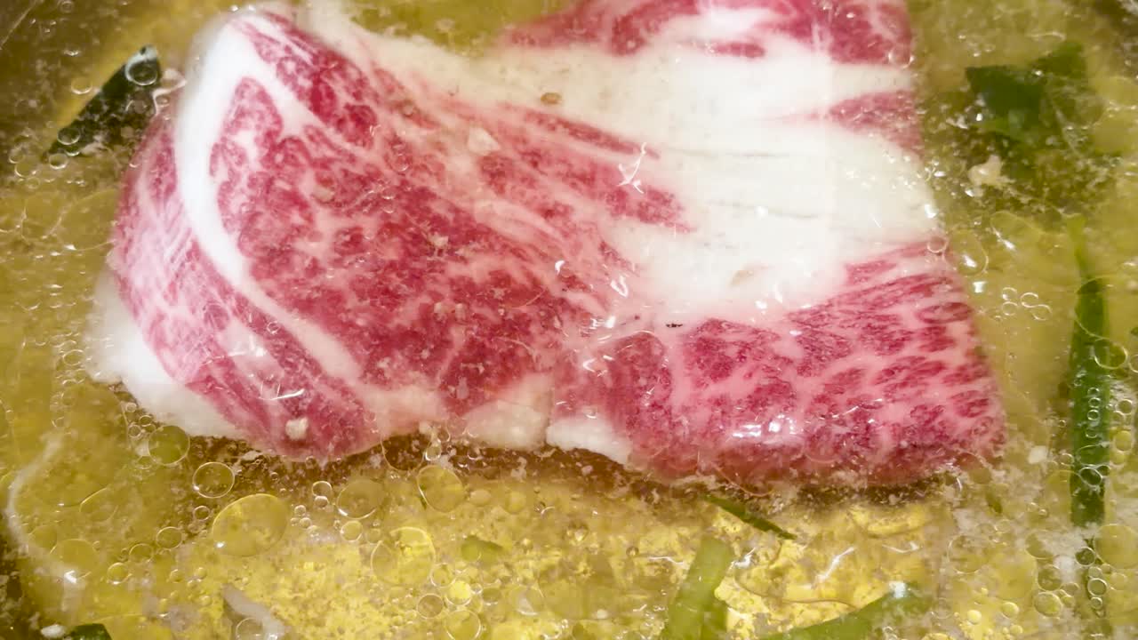 Thin marbled beef cooks in bubbling broth, close-up, bright lighting, minimal camera movement, overhead view