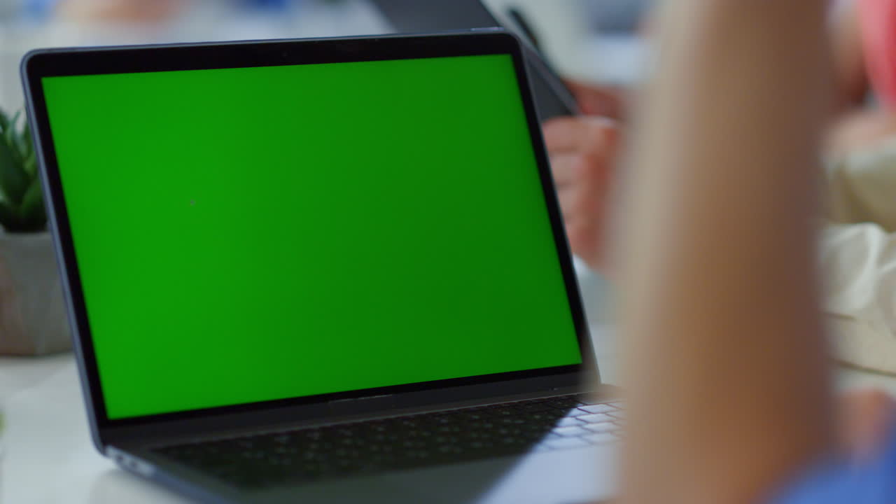 hombre desconocido haciendo una llamada de video con una computadora portátil de pantalla verde. hombre agitando la mano.