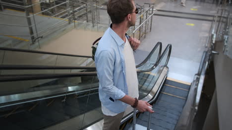 man on escalator in airport terminal