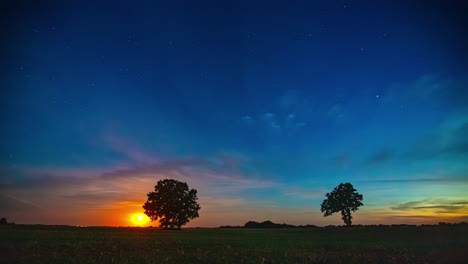 the moon setting on a starry night over fields of harvested crops - time lapse