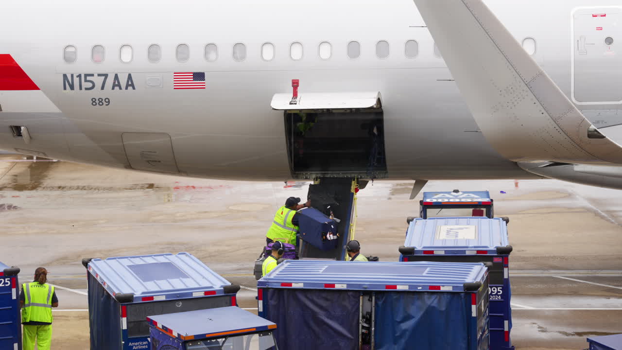 Airport workers unloading luggage from the airplane, establishing shot