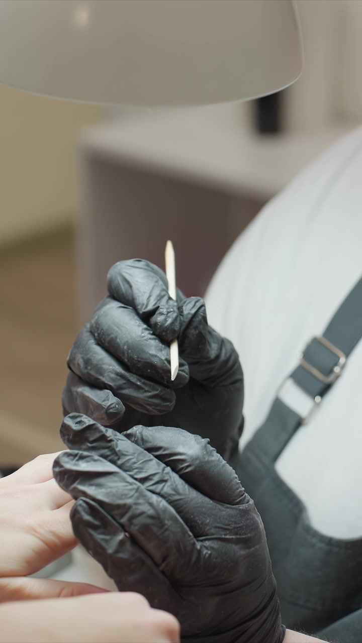 Gloved fingers carefully clean and detail another person foot under soft lighting focusing on precise nail or cuticle work in calm salon setting manicure