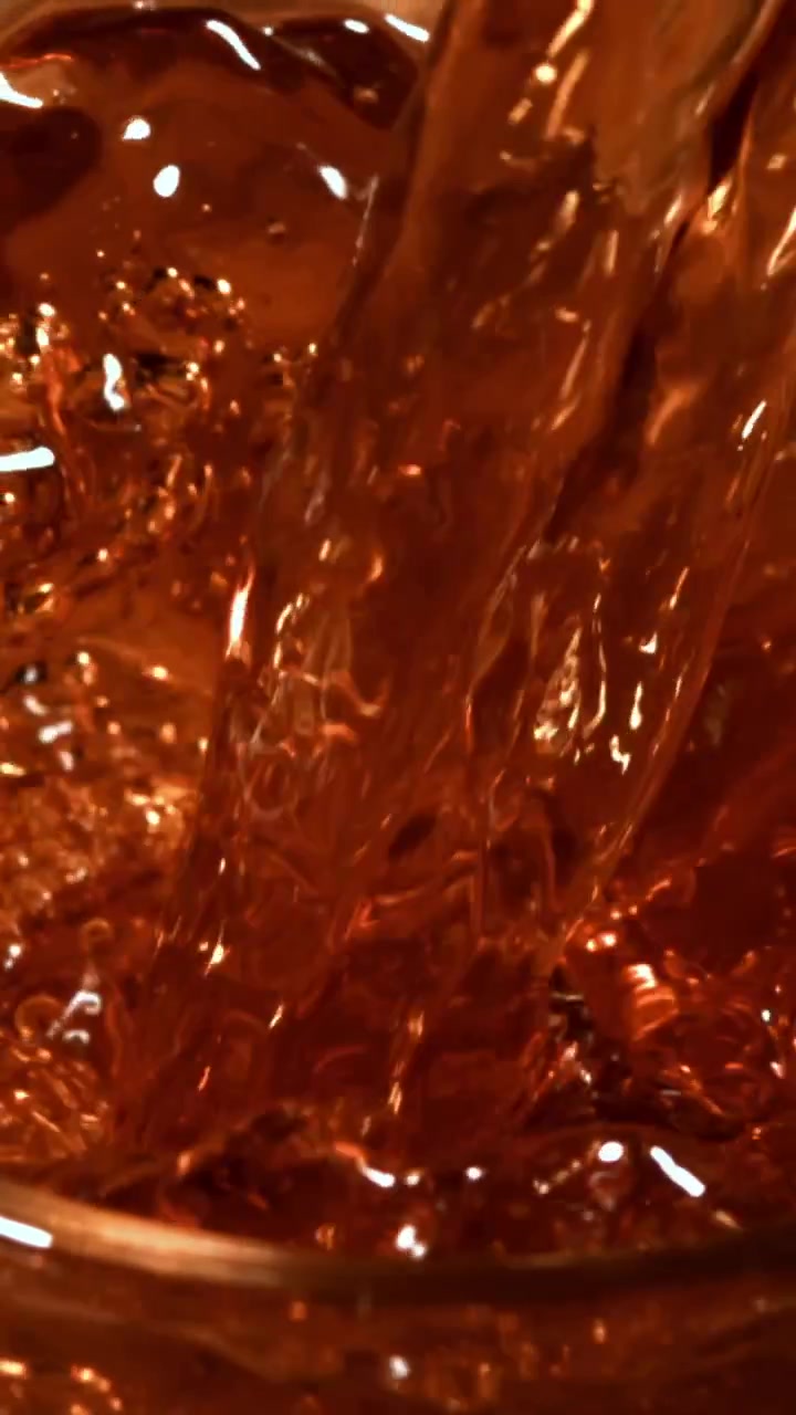Primo piano dinamico di liquido scuro che viene versato e schizza