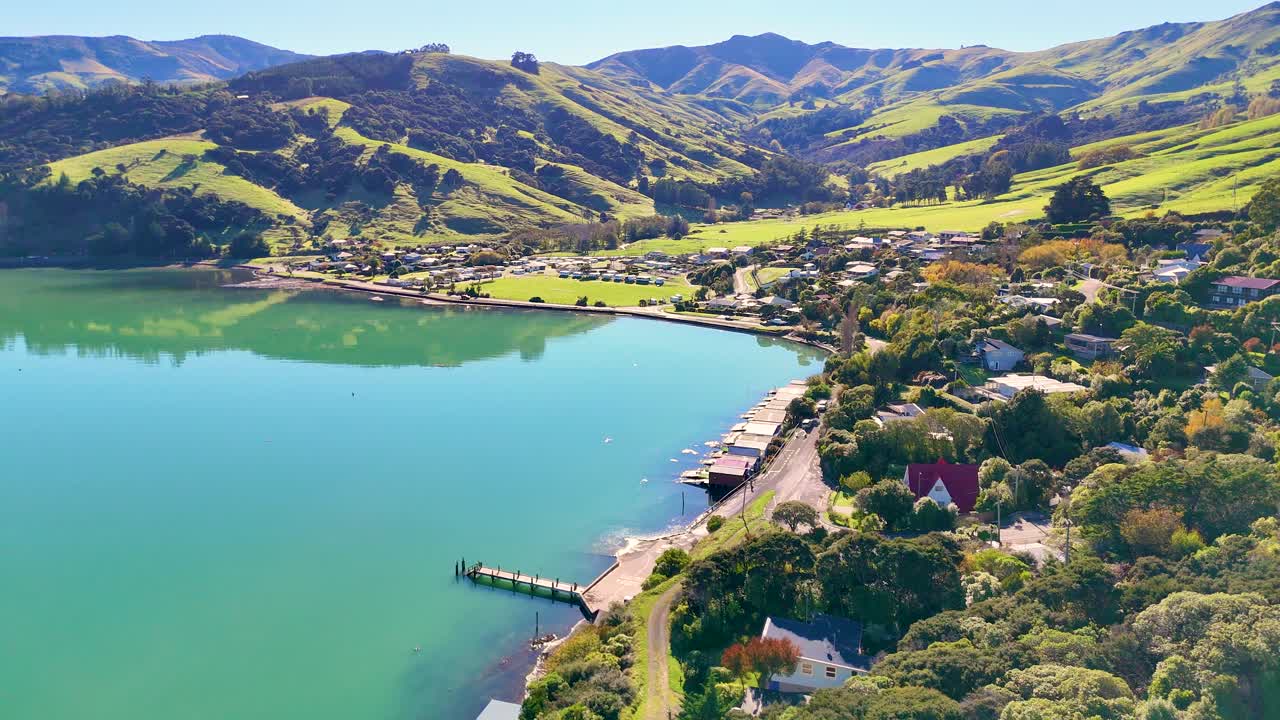 Aerial footage of Akaroa Harbour showcasing lush landscapes, calm waters, and vibrant greenery under bright daylight