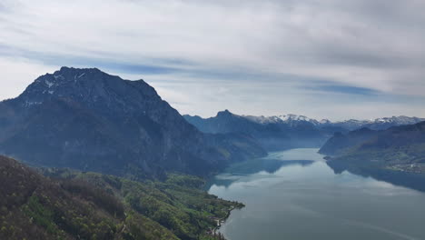 Desierto-Prístino-De-Los-Alpes,-Vista-Aérea-De-Las-Colinas-De-Las-Montañas-Y-Picos-Sobre-El-Pintoresco-Lago-En-La-Temporada-De-Primavera