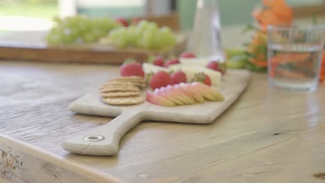 diapositiva de primer plano de aperitivo vegetariano con queso y fruta pomelo fresa en tabla de madera cortada