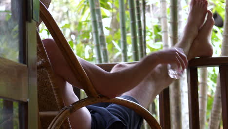 Young-man-relaxes-having-drink-on-terrace-enjoying-nature