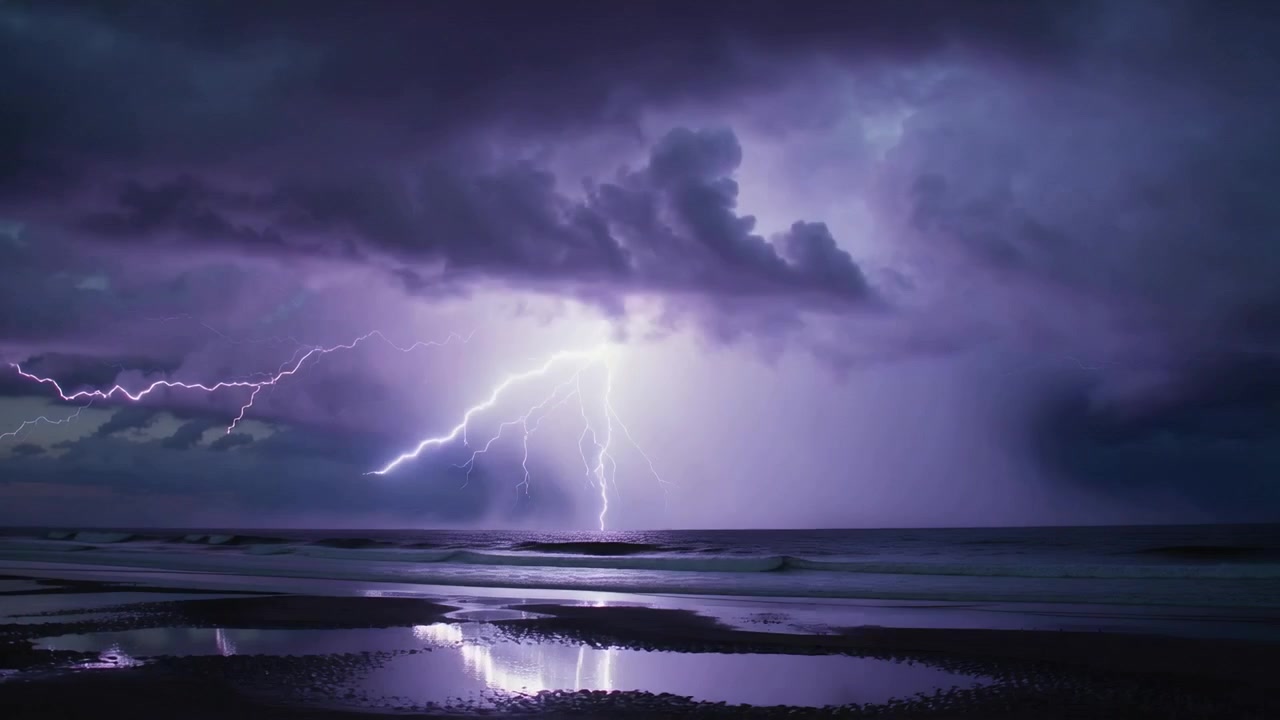 Striking ocean then broad lightning lighting storm cloud bank over coastal beach, with tidal pools