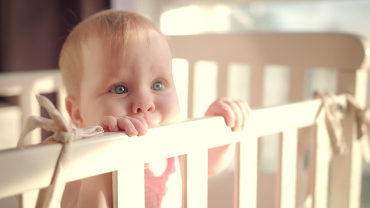 Bambina in piedi nel lettino a casa. Ritratto di bambina in piedi nella culla. Occhi di bambina.