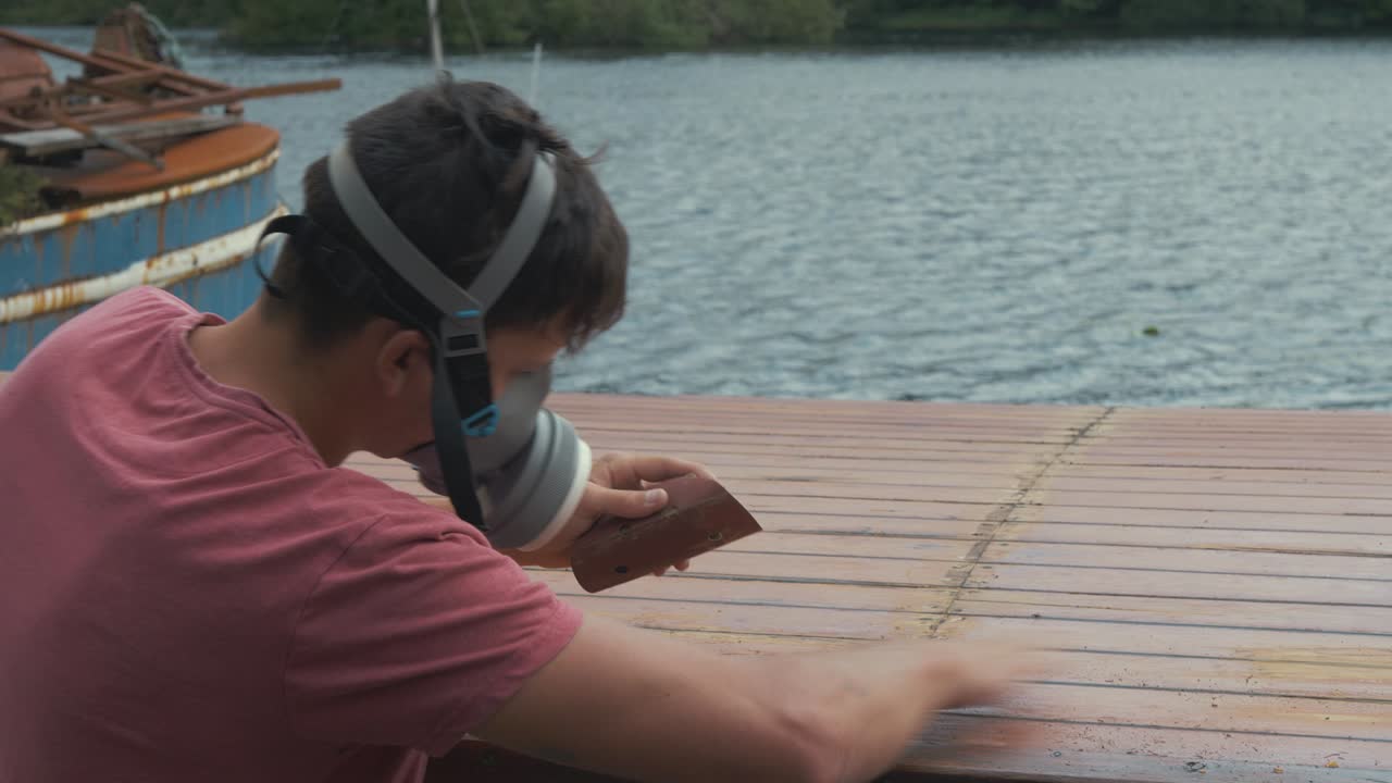 마스크를 쓰고 나무 보트 지붕 널빤지를 수동으로 샌딩