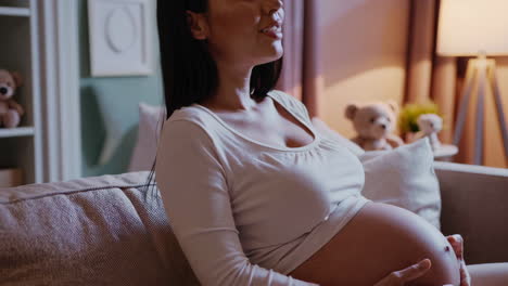 pregnant woman gently touching her belly at home
