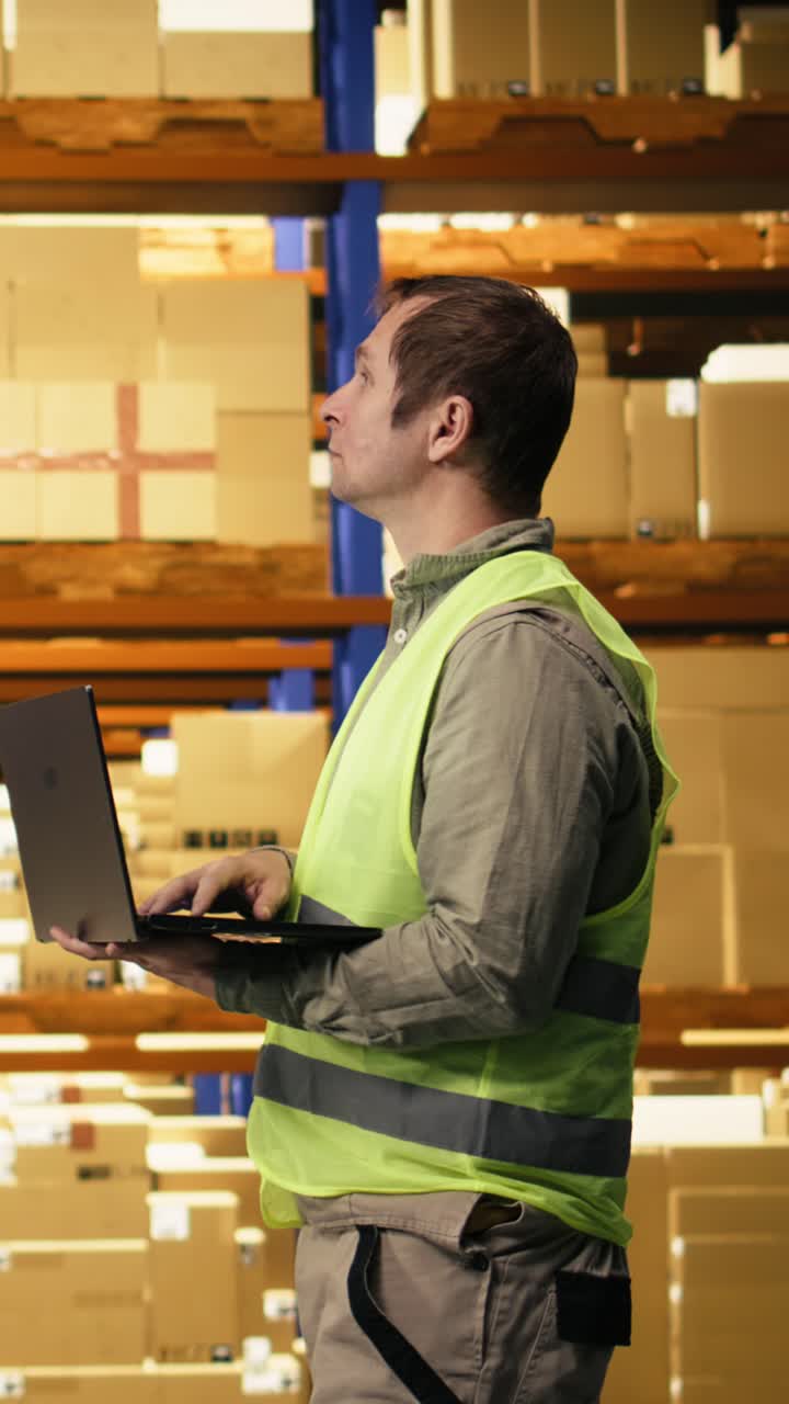 Video verticale: Personale maschile che opera con un laptop in un centro di distribuzione e-commerce