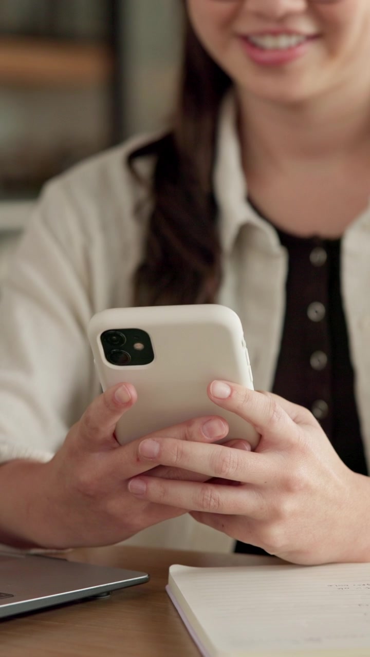 Giovane donna che usa lo smartphone alla scrivania in un ufficio moderno