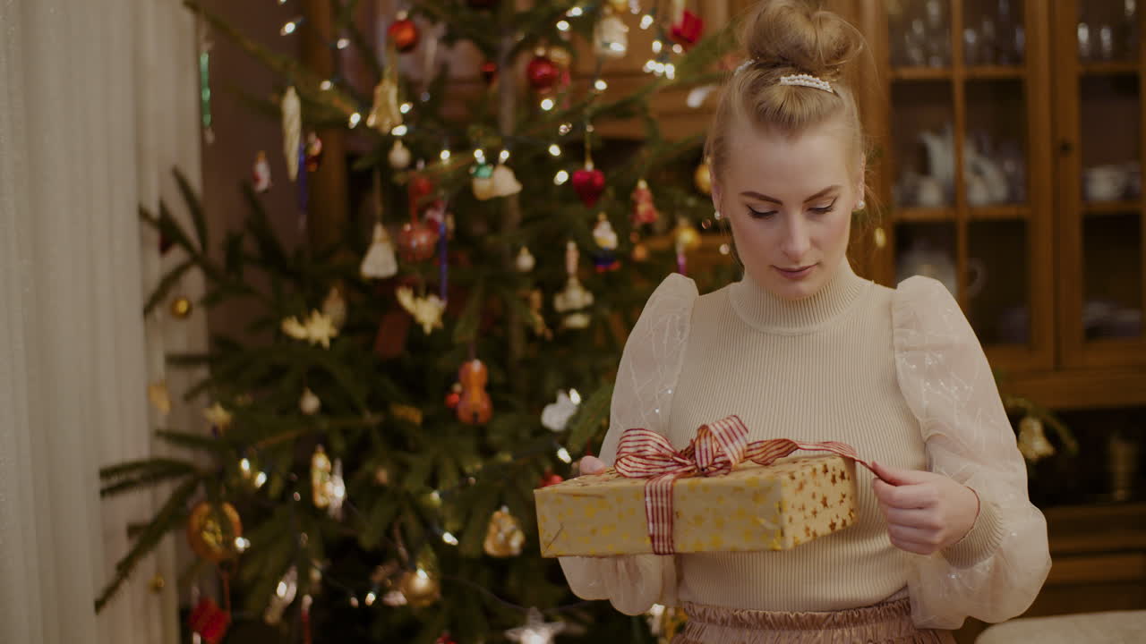 mujer curiosa sosteniendo un regalo de navidad en casa
