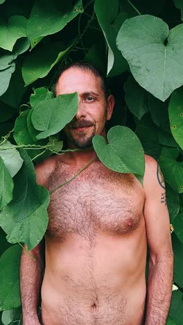 man hiding behind green leaves