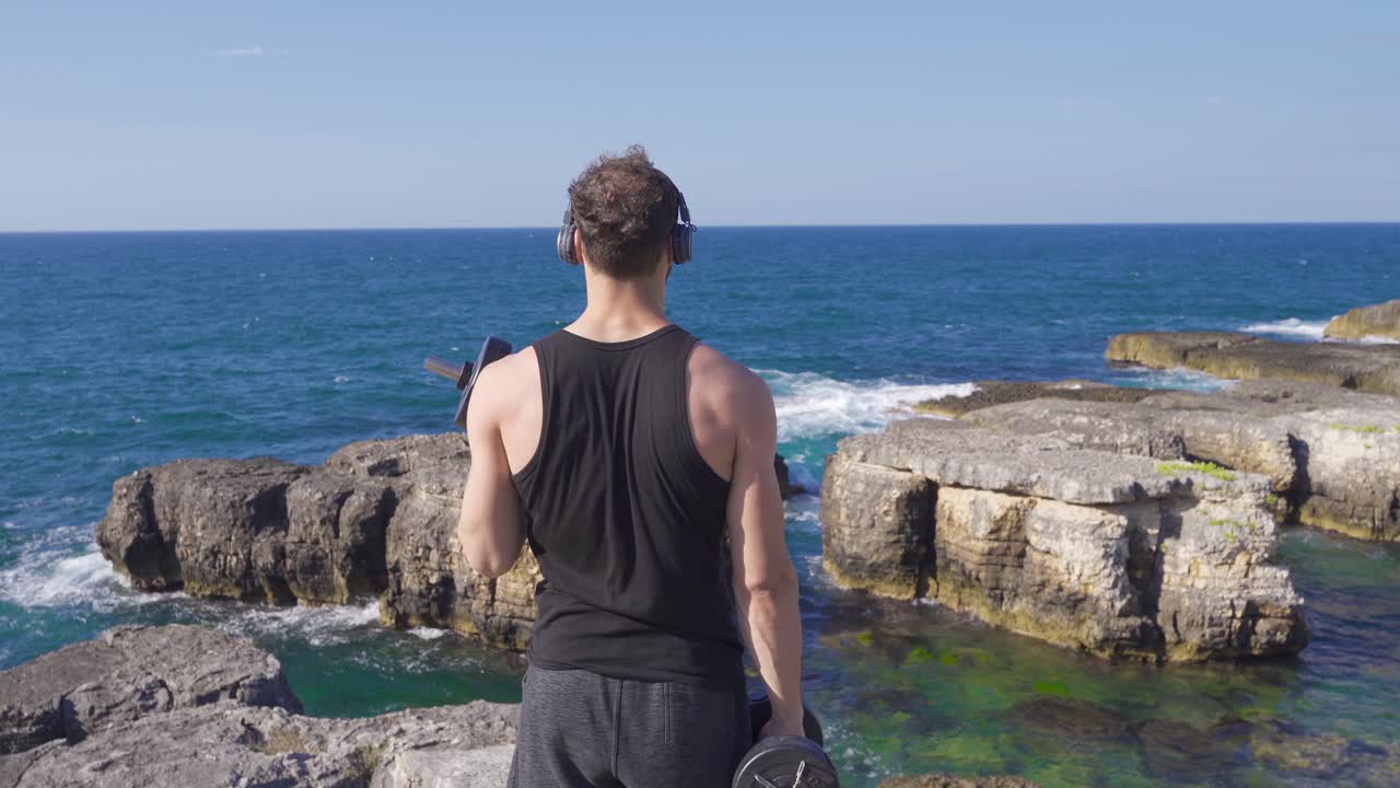 해변에서 몸무게를 들어 올리는 운동선수.