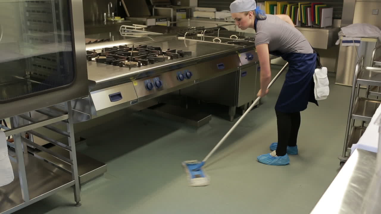 Cleaner wiping the floor in a kitchen