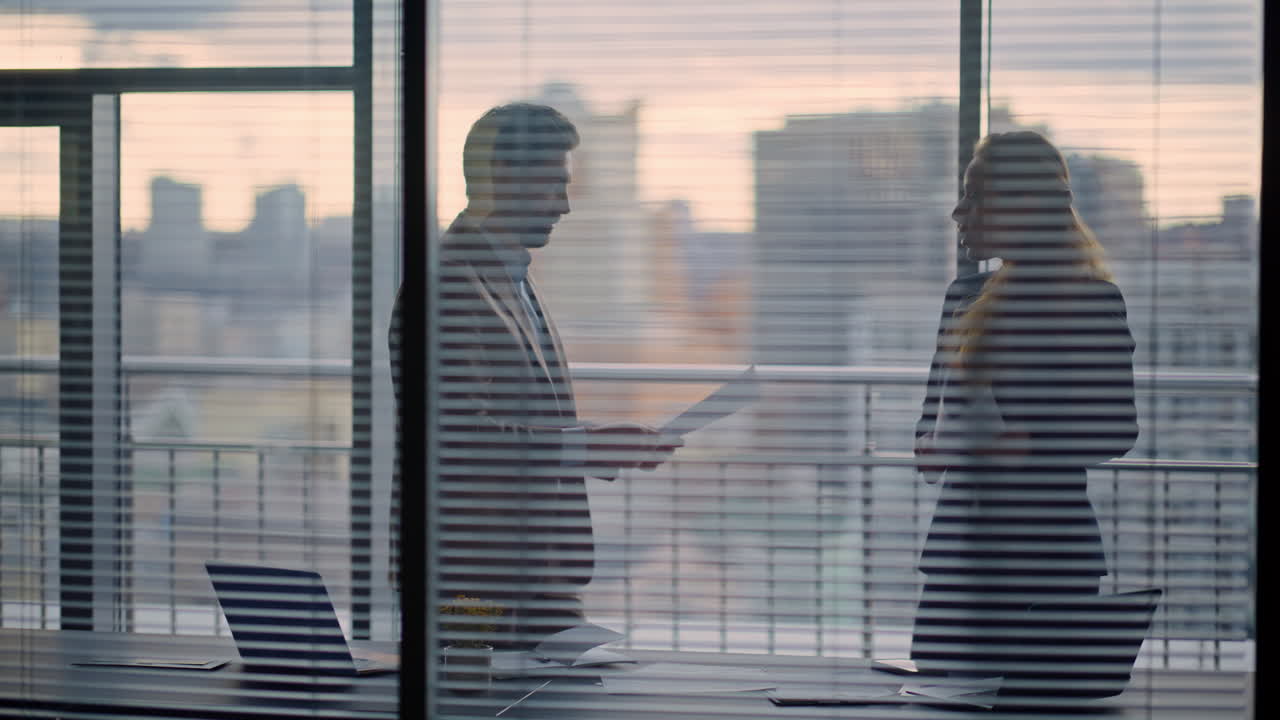 Accountants silhouettes watching papers standing at gloomy cityscape office