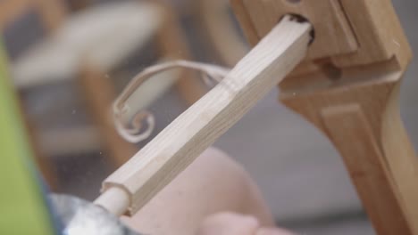 close-up view about the chair maker's wood shaping process with his tool, italy.