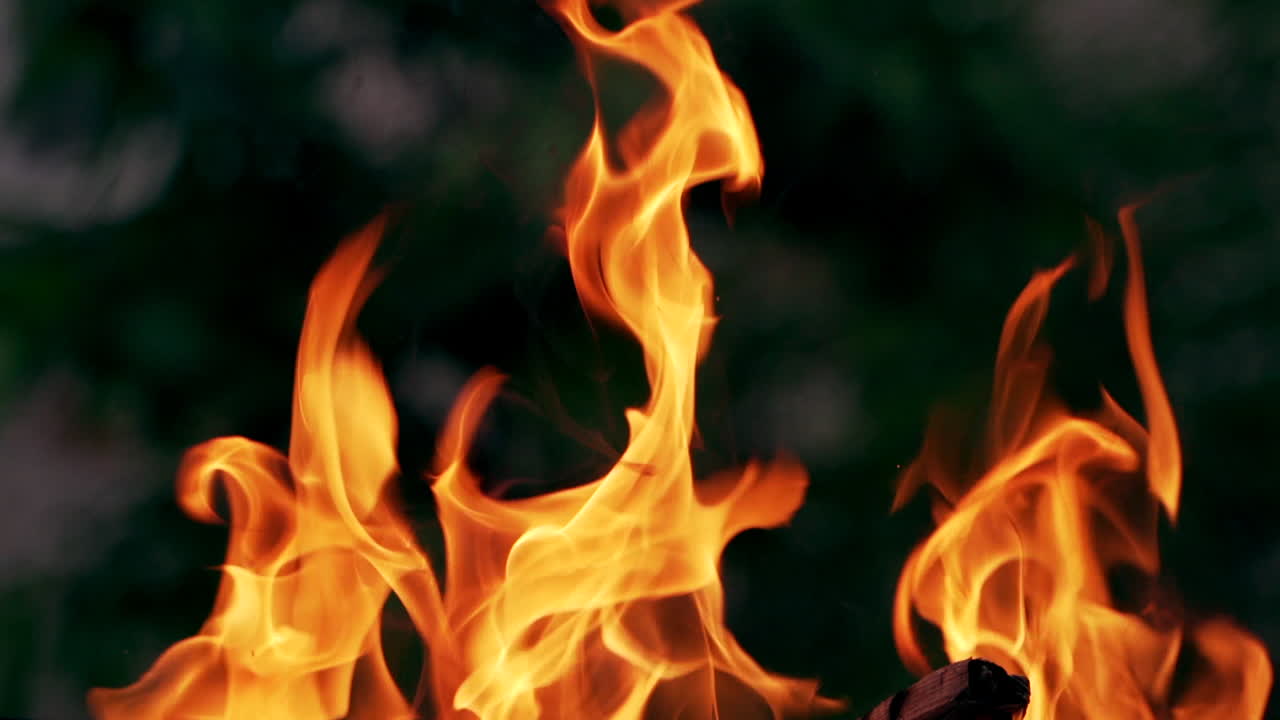 Vivid fire in the night. Orange flames close-up. Background of the fire. Beautiful fire burns brightly. Slow motion.