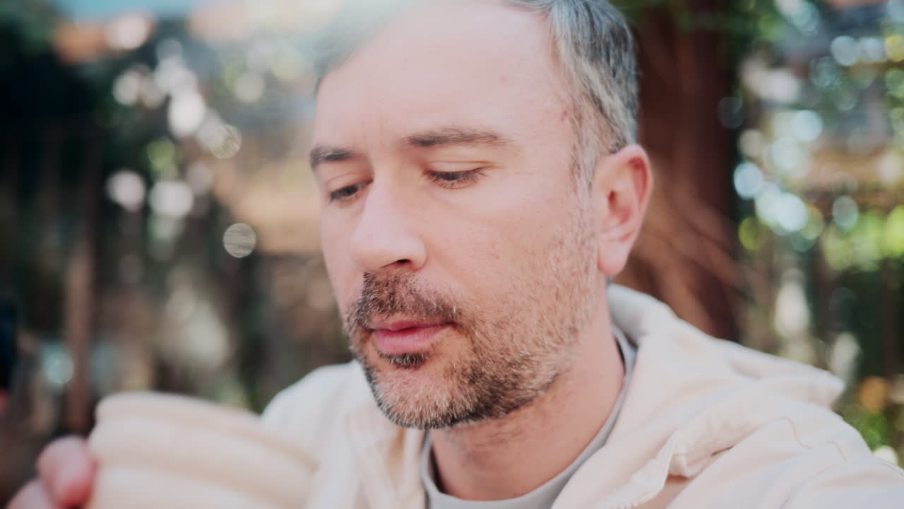 Close up of a man sipping coffee in natural sunlight at a cozy outdoor cafe