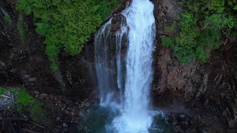 Majestic-orbital-shot-above-waterfall-and-cliffside-in-Evergreen-Forest-in-the-Pacific-Northwest