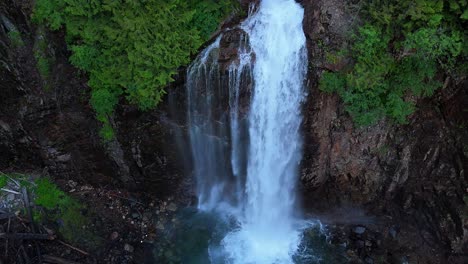 majestic orbital shot above waterfall and cliffside in evergreen forest in the pacific northwest