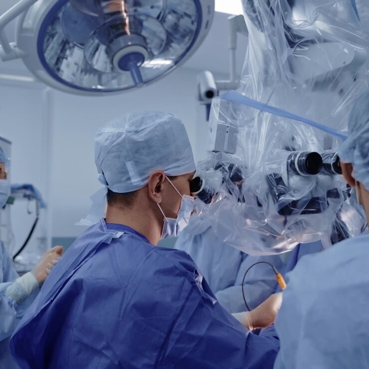Neurosurgeons with a microscope. Teamwork of professional doctors in blue medical uniform conduct a neurosurgery with modern medical equipment.