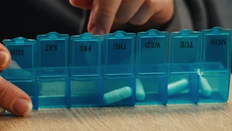 person taking pills from weekly pill organizer