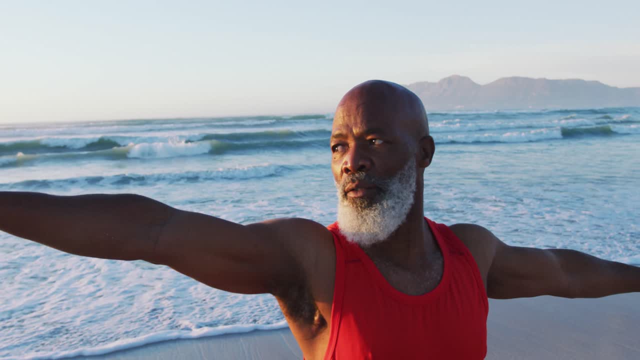 Senior african american man practising yoga at the beach