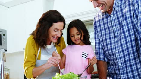 Parents-and-daughter-mixing-the-salad-in-kitchen