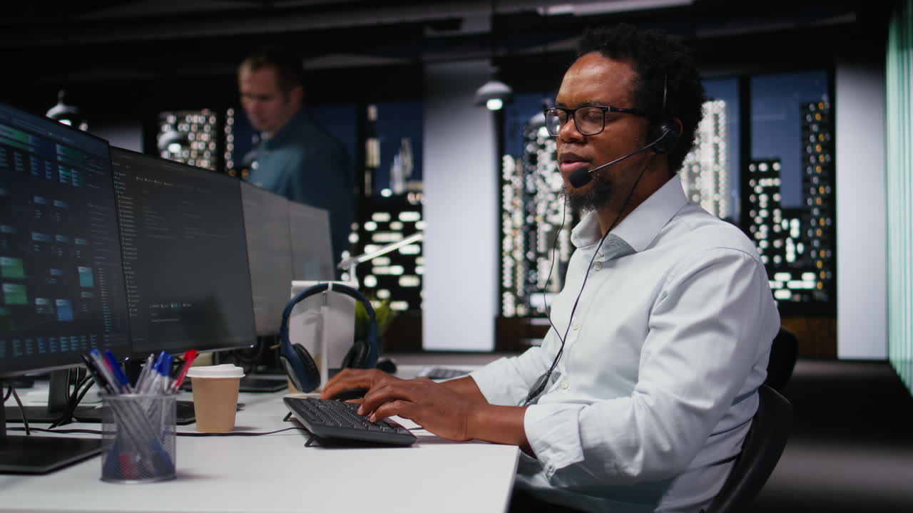 African American Man Working on Computer with Headset at Night