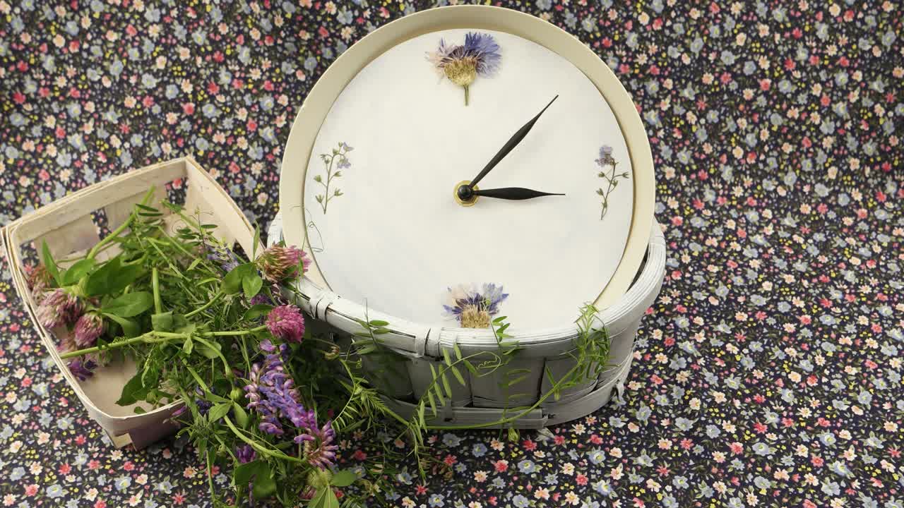 Clock and bouquet of wild flowers in the wicker box