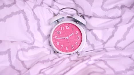 timelapse of a cute old-fashioned alarm clock on modern bed sheets
