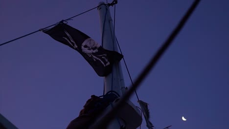 Eine-Piratenflagge-In-Zeitlupe-Weht-Im-Vind-Mit-Dem-Mond-Im-Hintergrund